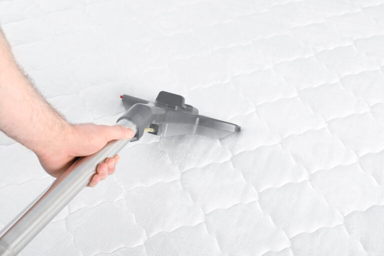 Man disinfecting mattress with vacuum cleaner, closeup