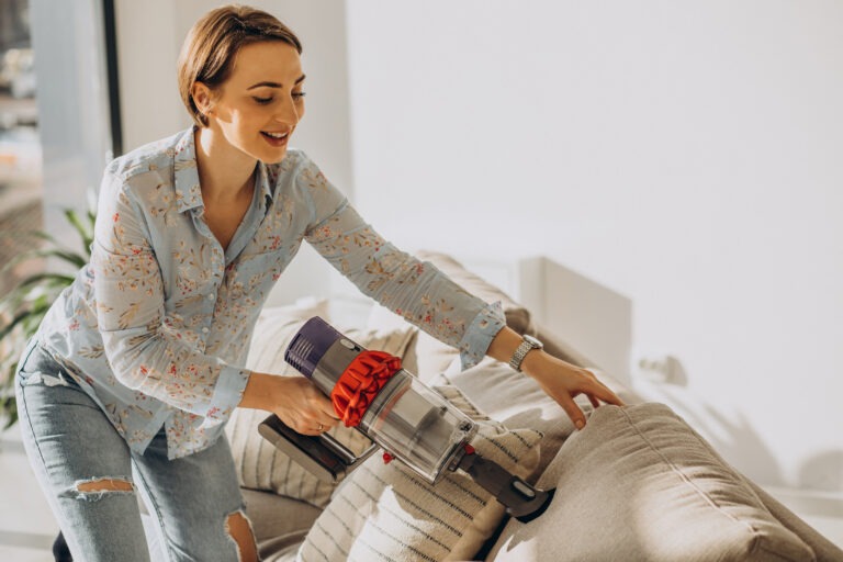 Young woman with rechargeable vacuum cleaner cleaning at home